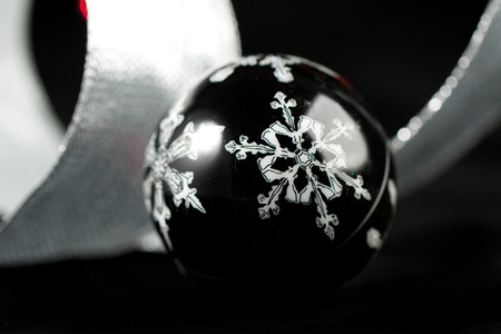 Black christmas ball with a white snowflakes on the black backgroundの写真素材