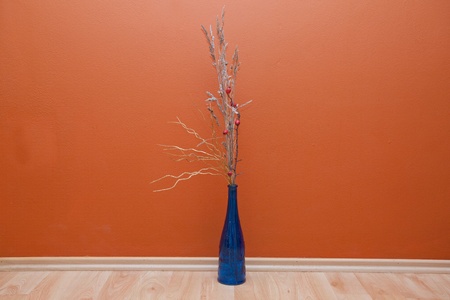 Bouquet in blue bottle on a floor near the orange wallの写真素材