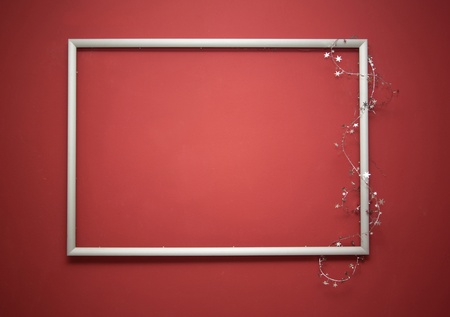 Empty frame with christmas garland on the red wallの写真素材