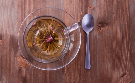 Transparent cup of a green tea with the teaspoon on the wooden tableの写真素材