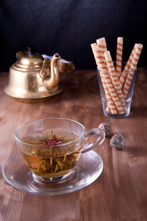 Transparent cup of a green tea with the sweet wafers and old teapotの写真素材