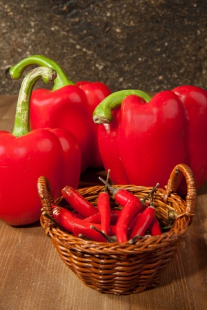 Basket of red hot chili peppers with paprika on the wooden deskの写真素材