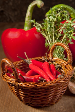 Basket of red hot chili peppers with herbs and paprika on the wooden deskの写真素材