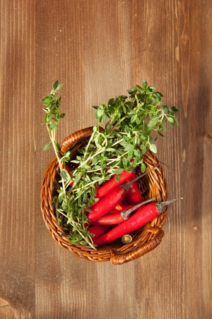 Basket of red hot chili peppers with herbs on the wooden backgroundの写真素材