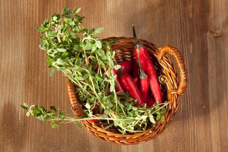 Basket of red hot chili peppers with herbs on the wooden backgroundの写真素材