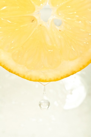 Single cross section of lemon with the drop of waterの写真素材