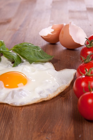 Fried egg in a wooden desk with tomato and fresh herbの写真素材
