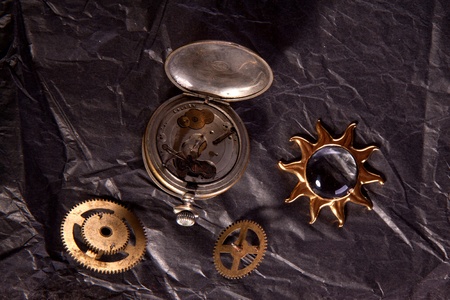 Composition of old clockwork and little golden sun on the black paperの写真素材