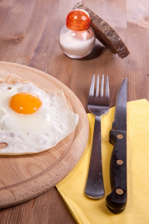 Fried egg on a wooden desk with salt and loaf of breadの写真素材