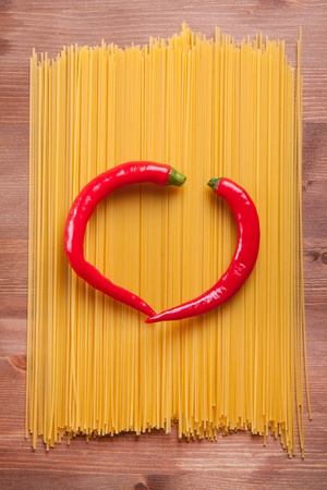 Tow red hot chili peppers as a heart on the italian spaghettiの写真素材