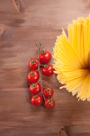 Bunch of spaghetti on a wooden table with cherry tomatoの写真素材