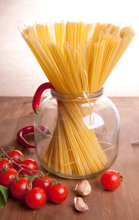 Composition of pasta, garlic, pepper and tomato on a wooden tableの写真素材