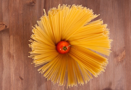 Bunch of spaghetti on a wooden table with cherry tomatoの写真素材