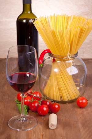 Glass of red wine near italian spaghetti and vegetables for pastaの写真素材