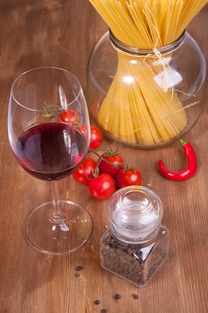 Glass of red wine near italian spaghetti and vegetables for pastaの写真素材