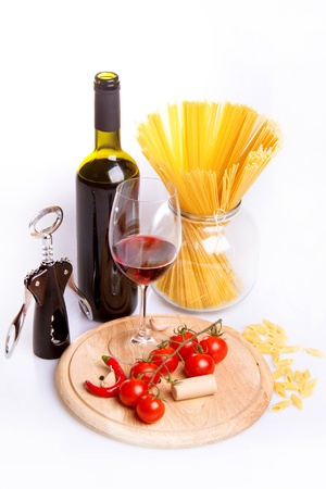 Glass of red wine near italian spaghetti and vegetables for pastaの写真素材