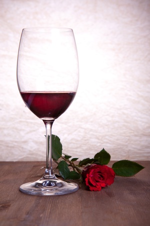 Glass of red wine with beautiful red roseの写真素材