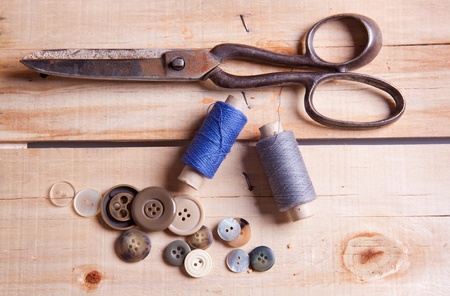 Old scissors, cottons and buttuns on wooden deskの写真素材