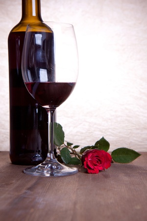 bottle and glass with red wine and beautiful red roseの写真素材