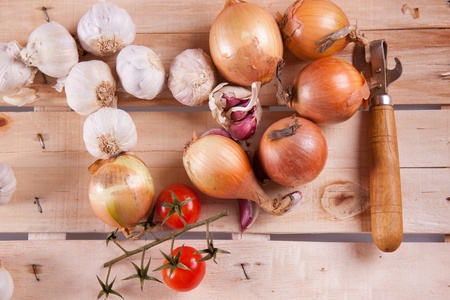 Onion, garlic and tomato on a wooden desk in sun shineの写真素材