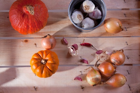 Onion, garlic and pumpkins on a wooden desk in sun shineの写真素材