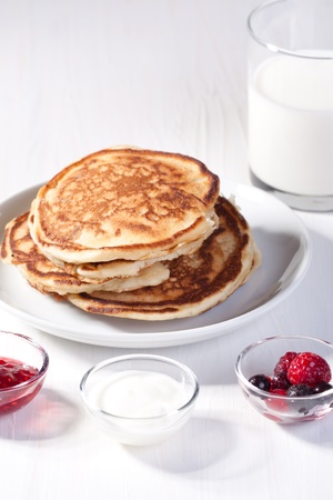 Breakfast with pancakes, fresh berries and strawberry jam, served on white tableの写真素材