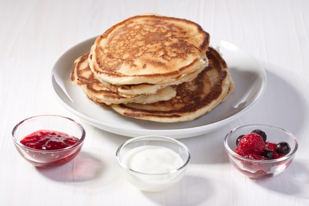 Breakfast with pancakes, fresh berries and strawberry jam served on white tableの写真素材