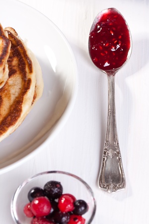 Pancakes, fresh berries and silver teaspoon with strawberry jamの写真素材