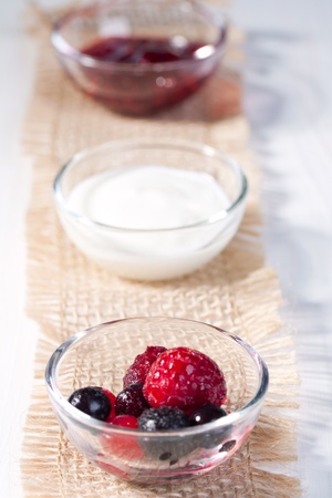 MIx of different berries and cream in little bowls の写真素材