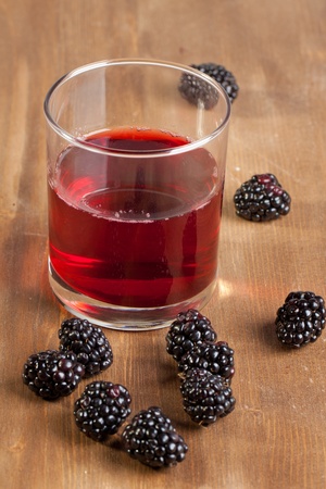 Fresh blackberries and glass of juice on wooden tableの写真素材