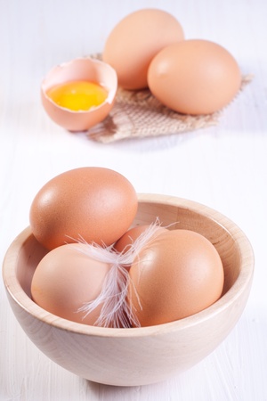 Wooden bowl with eggs and broken egg の写真素材