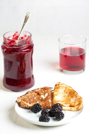 Plate of pancakes with fresh blackberries and pot of jamの写真素材