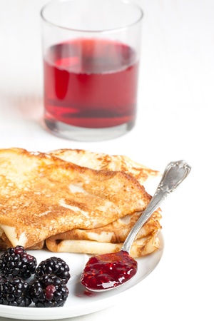 Plate of pancakes with fresh blackberries and glass of juiceの写真素材