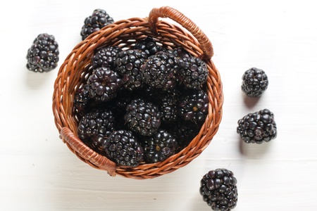 Blackberries in basket on white tableの写真素材