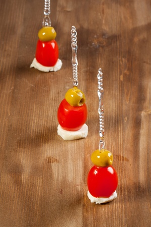 Snacks with green olives and fresh tomato on wooden tableの写真素材