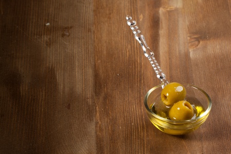 Snacks with green olives in little glass bowl on wooden backgroundの写真素材