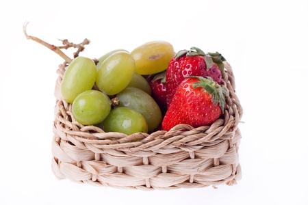 Green grapes and strawberry in basket isolated over whiteの写真素材