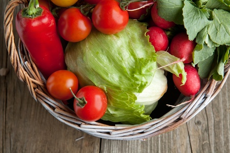 Top view on basket with fresh red paprika, tomato, radish and green saladの写真素材