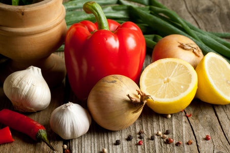 Onion, red paprika, garlic, lemon and chili pepper on old wooden tableの写真素材