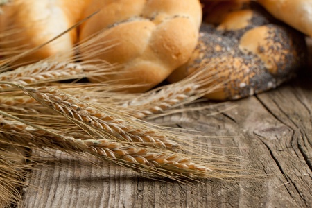 Dried ears of corn on old wooden table with fresh bread as backgroundの写真素材