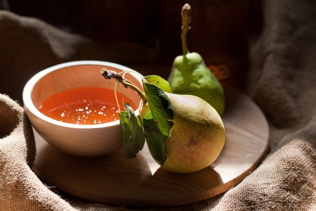 Wooden bowl with fresh honey and pears in the sunshine on wooden tableの写真素材