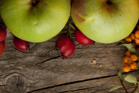 Background with green apples and autumn berries on old wooden tableの写真素材
