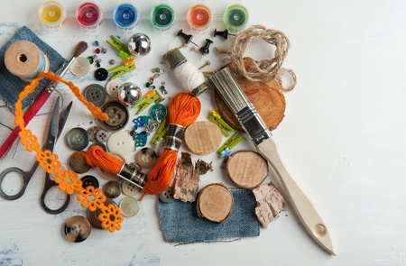 Still life of spool of thread, buttons, scissors and brushes on white tableの写真素材