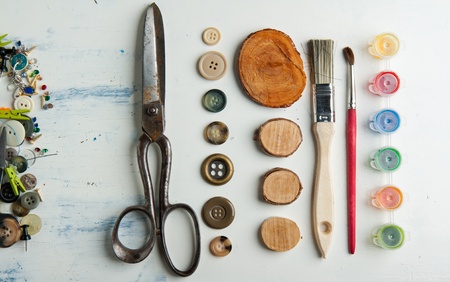 Still life of spool of thread, buttons, scissors and brushes on white tableの写真素材