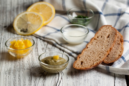 Sauceboats with different sauces and seasonings with lime and bread on white wooden table