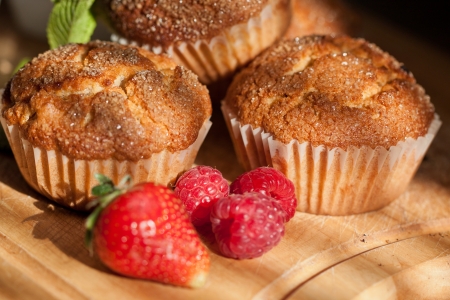 Close-up of muffins with fresh strawberries and raspberries on wooden desk  See series の写真素材