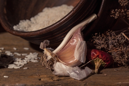 garlic on brown wooden table with ceramics bowls and dried pepper with dried spices の写真素材