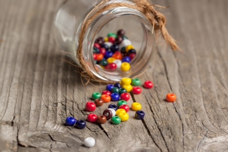colorful beautiful glass beads with glass jar on old wooden tableの写真素材