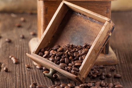 broken old-fashioned coffee grinder and roasted coffee beans on brown wooden table の写真素材