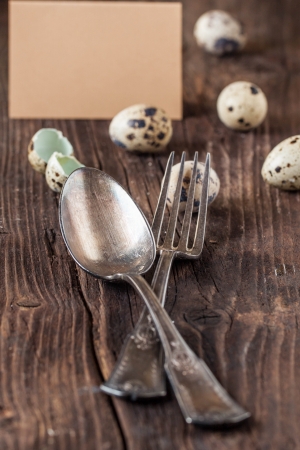 Easter table setting with quail eggs and vintage silverware on old wooden tableの写真素材